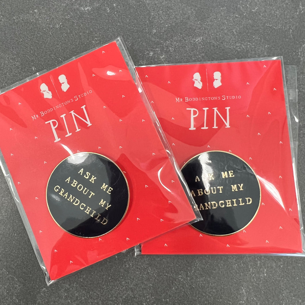 Two black pins with gold writing reading 