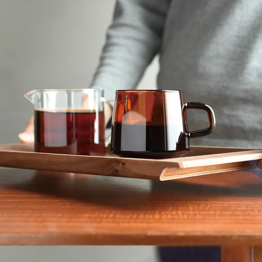 male model holding the kinto walnut tray with two coffees on it